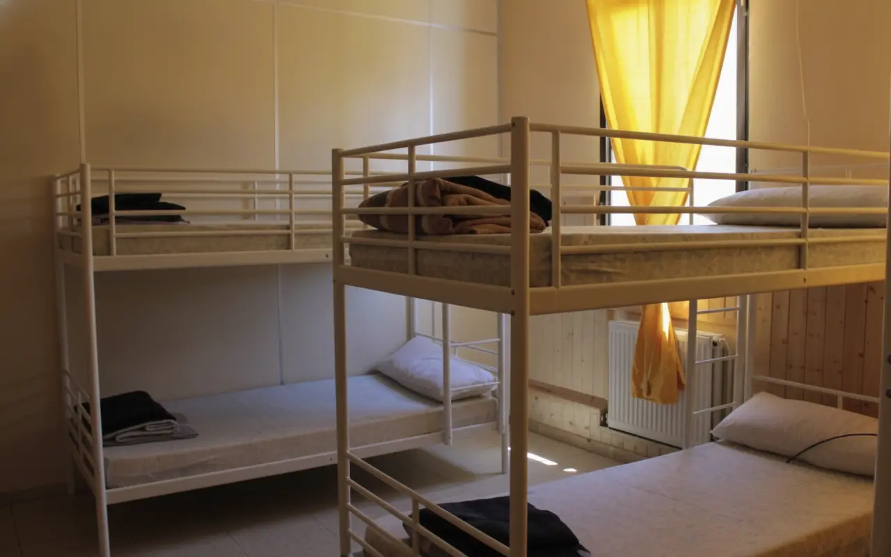 Literas con ropa de cama junto a una ventana con cortina amarilla