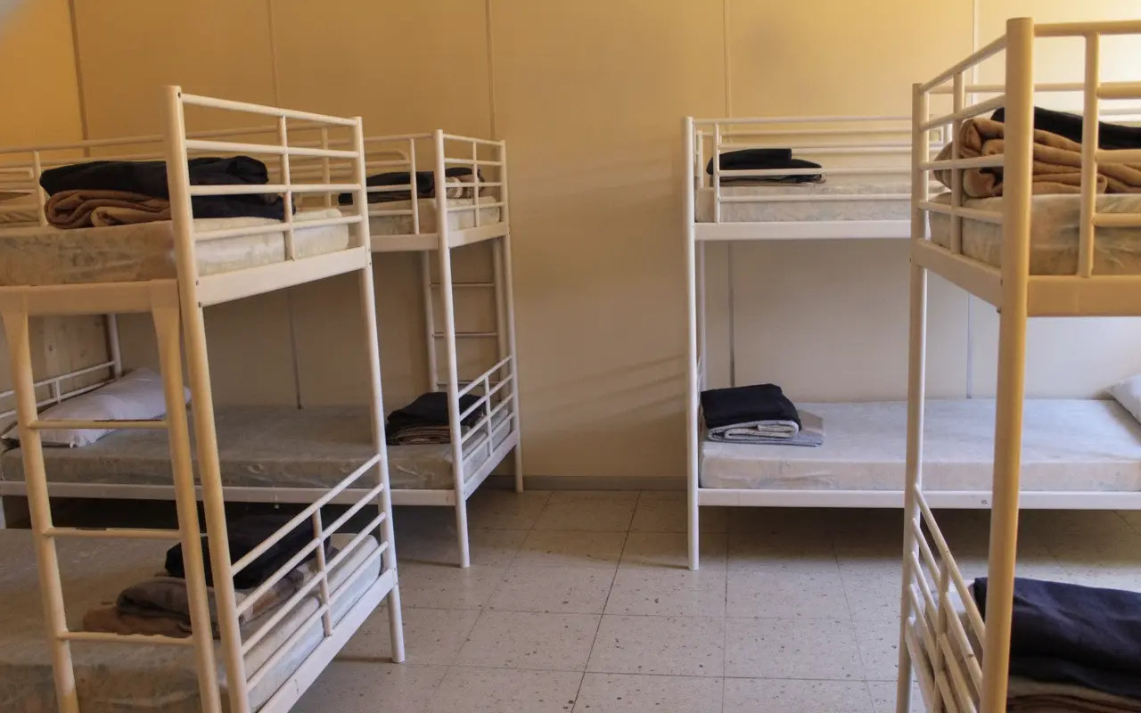 Literas de una habitación del albergue con colchones y espacio para las mochilas