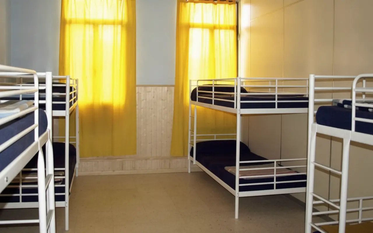 Dormitorio con literas metálicas y cortinas amarillas
