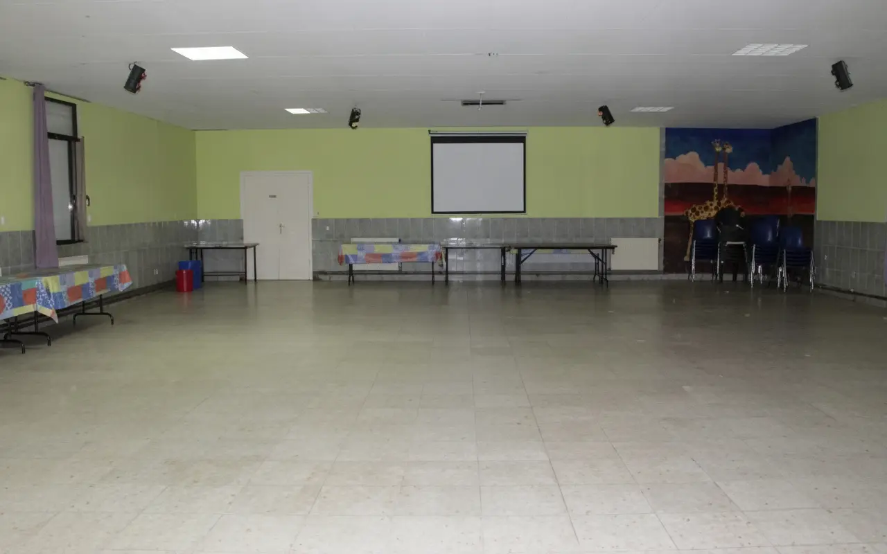 Sala diáfana con pantalla de proyección y murales en la pared
